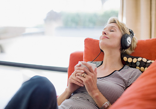 Woman listening to music after learning about her heart palpitation as a hormonal symptom