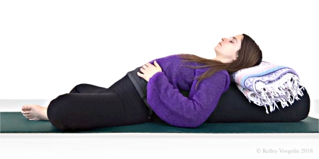 Woman doing Reclining Bound Angle Pose in yoga to reduce stress