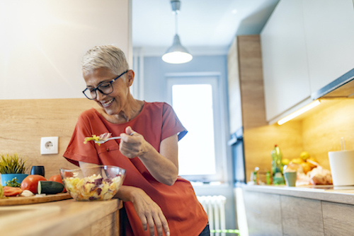 Woman eating food to reduce inflammation and bone loss during menopause.