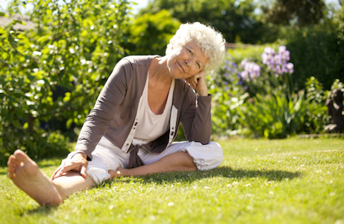 Older woman sitting in the grass thinking about her bone health risk factors.