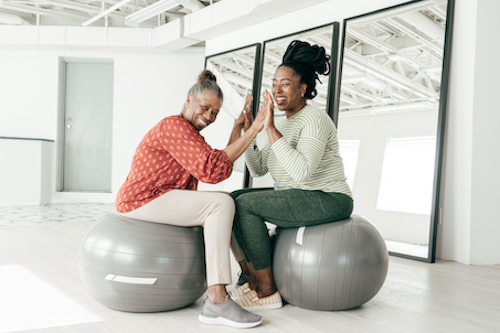 Woman in menopause on exercise ball with her daughter, talking about hormonal balance in menopause.